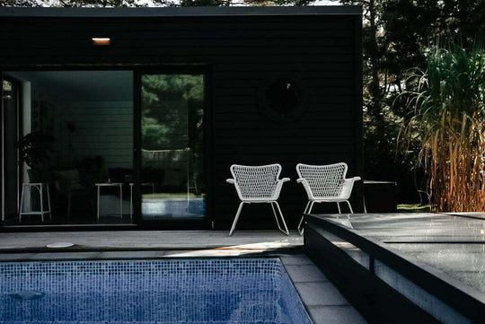 en pool med pooltak, ett uterum och 2 vita stolar vid poolkanten.